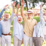 Group of older adults raising their hands joyfully outdoors in an independent living Chattanooga community